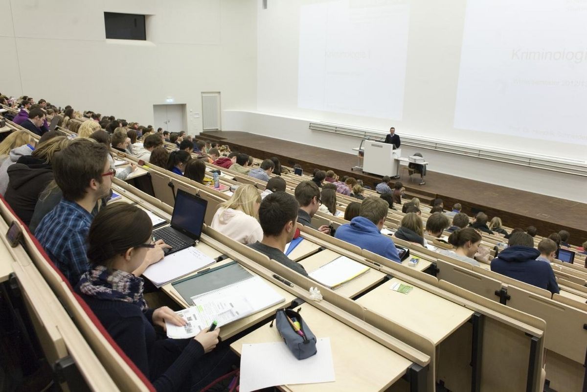 zur Vergrößerungsansicht des Bildes: Foto: Vorlesung im vollbesetzten Audimax, am Rednerpult steht ein Professor