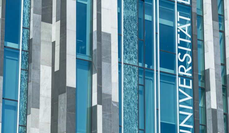 Glasfassade des Augusteums der Universität Leipzig, vertikal ist der Schriftzug „Universität” zu erkennen.