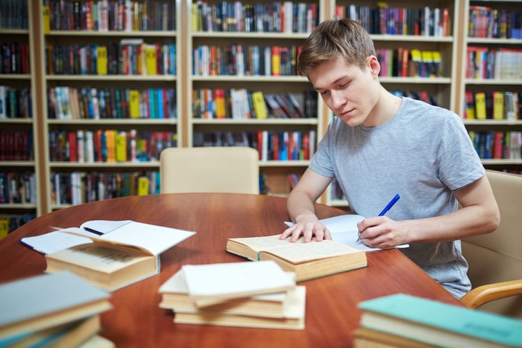 Studierender recherchiert für eine Forschungsarbeit in der Bibliothek. Foto: Colourbox.