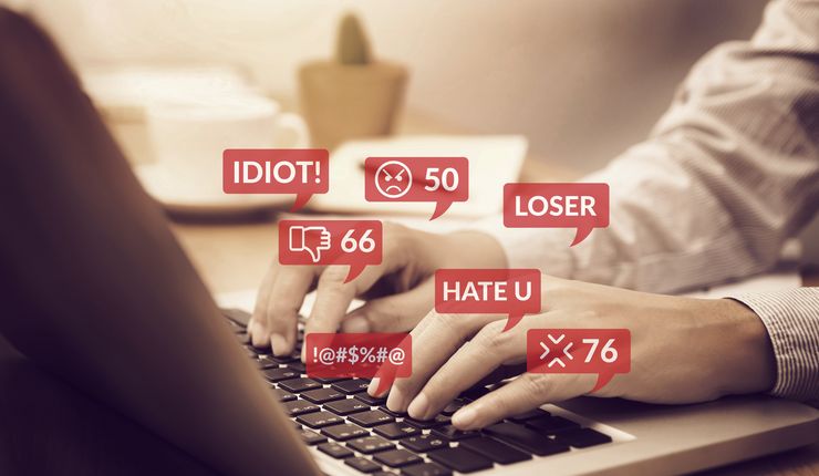 Hände auf Laptop-Tastatur, Textbeleidigungen angezeigt, Digitaler Hass