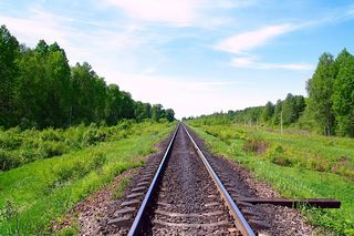 Bahngleise die innerhalb einer grünen Landschaft verlaufen