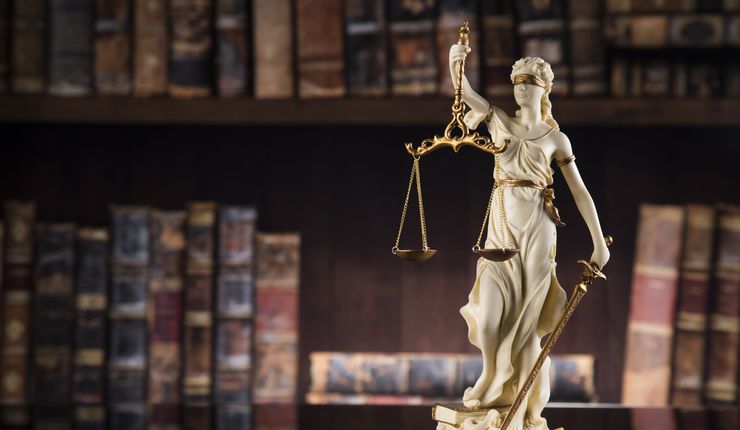 Kleine Statue von Justitia, im Hintergrund Rechtsbücher