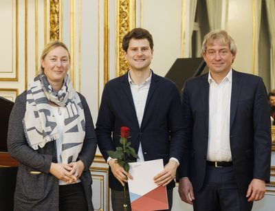 Niklas Wais (Mitte) wird mit dem Nachwuchspreis Lehre der Universitätsgesellschaft ausgezeichnet. Elke Netz, Referentin des Prokanzlers für Talententwicklung, und Dr. Jörg Wadzack, Kanzler der Universität gratulieren. Foto: J. E. Mathias.