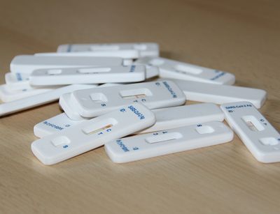 Schnelltest mit negativen Testergebnis auf einem kleinen Haufen auf einem Holztisch.