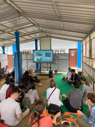 Farbfotografie der Teilnehmenden des Workshops beim Besuch einer Islamic Boarding School, die in Indonesien Pesantren genannt werden. Die Personen sitzen in einem Halbkreis auf dem Boden. 