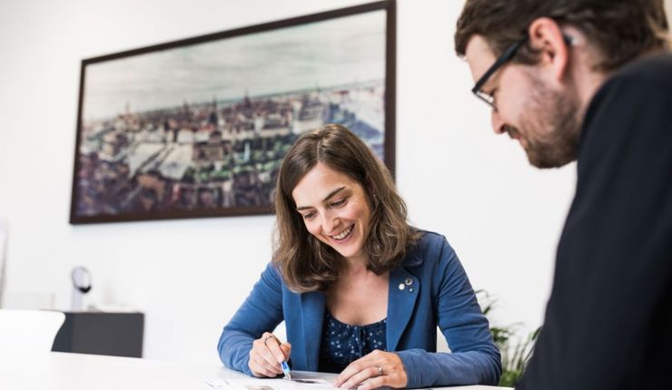 Zwei Personen sitzen zusammen an einem Tisch und führen ein Gespräch.