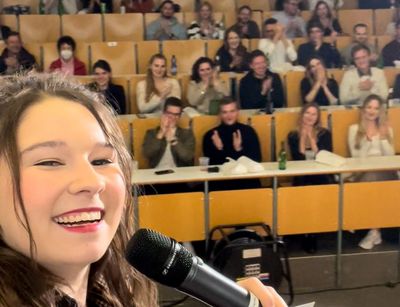 Elisabeth mit einem Mikrofon vor Publikum in einem Hörsaal