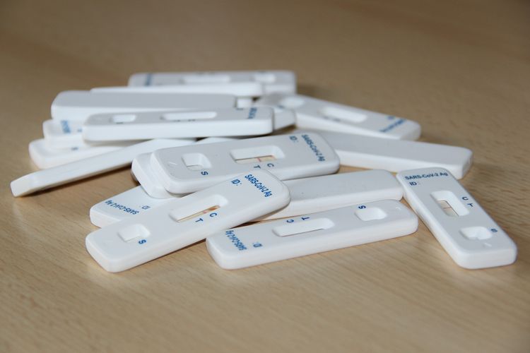 Schnelltest mit negativen Testergebnis auf einem kleinen Haufen auf einem Holztisch.