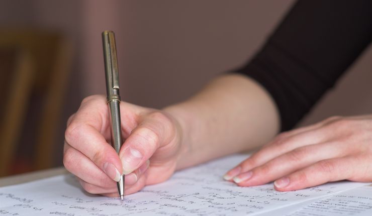 Eine Hand mit Kugelschreiber beim Ausfüllen eines Dokuments