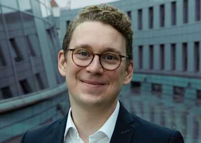 Mann mit kurzen blonden Haaren und Brille schaut freundlich in die Kamera