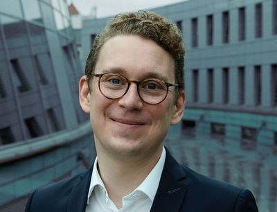 Mann mit kurzen blonden Haaren und Brille schaut freundlich in die Kamera