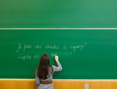 Eine Studierende schreibt im Sprachenzentrum auf Französisch an die Tafel.