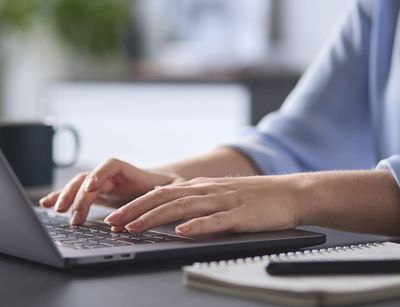 Farbfoto: Detailaufnahme Frau tippt am Laptop.