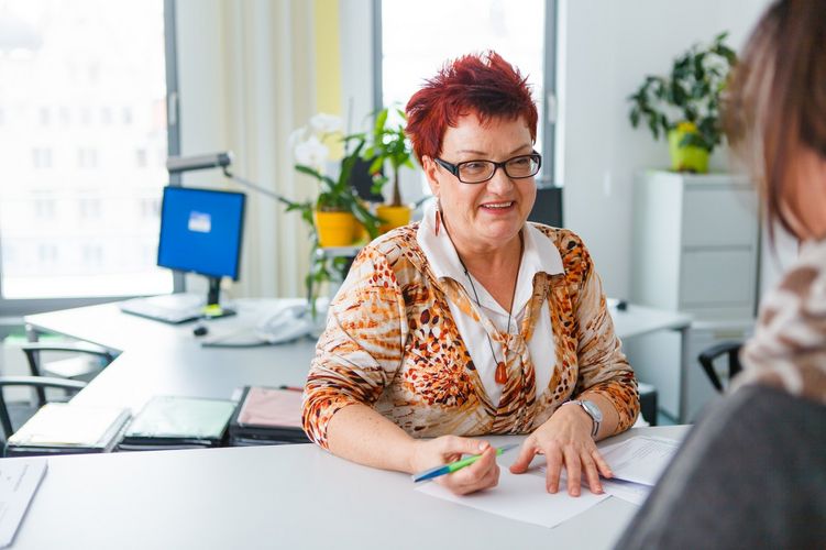 Eine Person lässt sich von einer Frau beraten. Sie sitzen sich im Büro gegenüber, Foto: Christian Hüller 