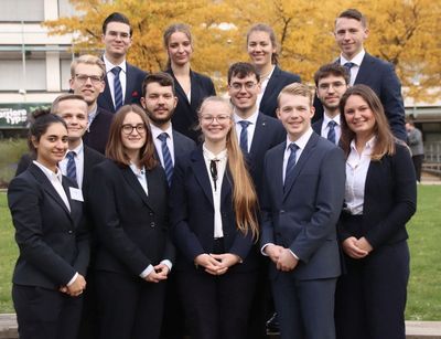 Auf dem Bild sind junge Menschen mit schwarzen Anwaltsroben zu sehen.