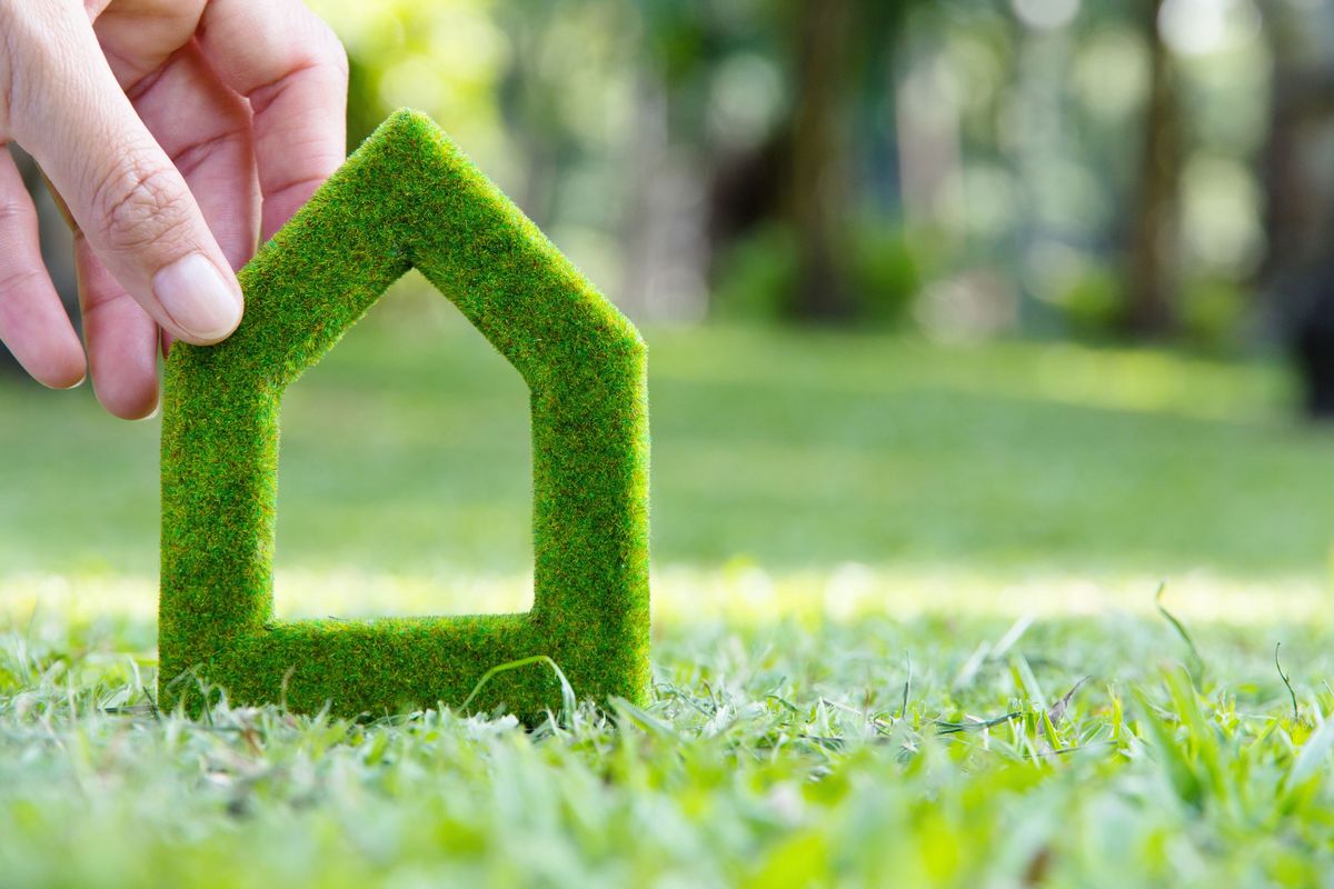 Auf dem Symbolfoto hält eine Hand ein stilisiertes Haus aus Gras.