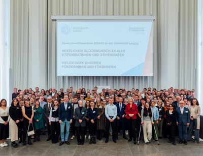 Förderer und Stipendiaten des Deutschlandstipendiums stehen für ein Gruppenfoto zusammen auf der Bühne im Paulinum