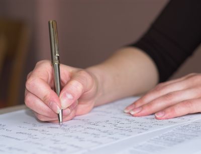 Eine Hand mit Kugelschreiber beim Ausfüllen eines Dokuments