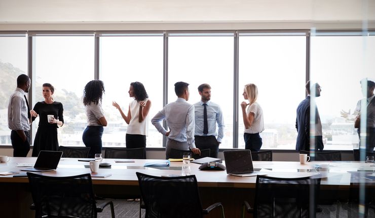 Mitarbeiter:innen unterhalten sich angeregt während einer Meetingpause. Foto: Colourbox.