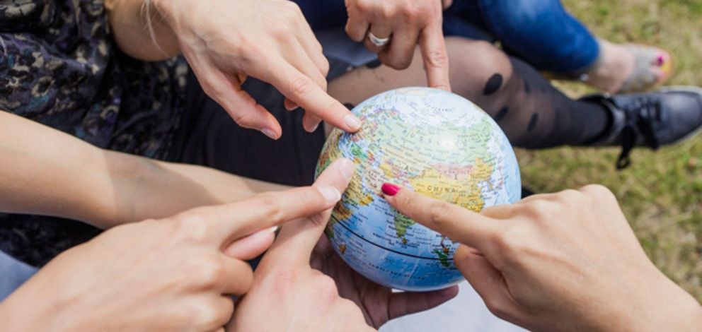 Fingers pointing at a globe. Photo: Christian Hüller